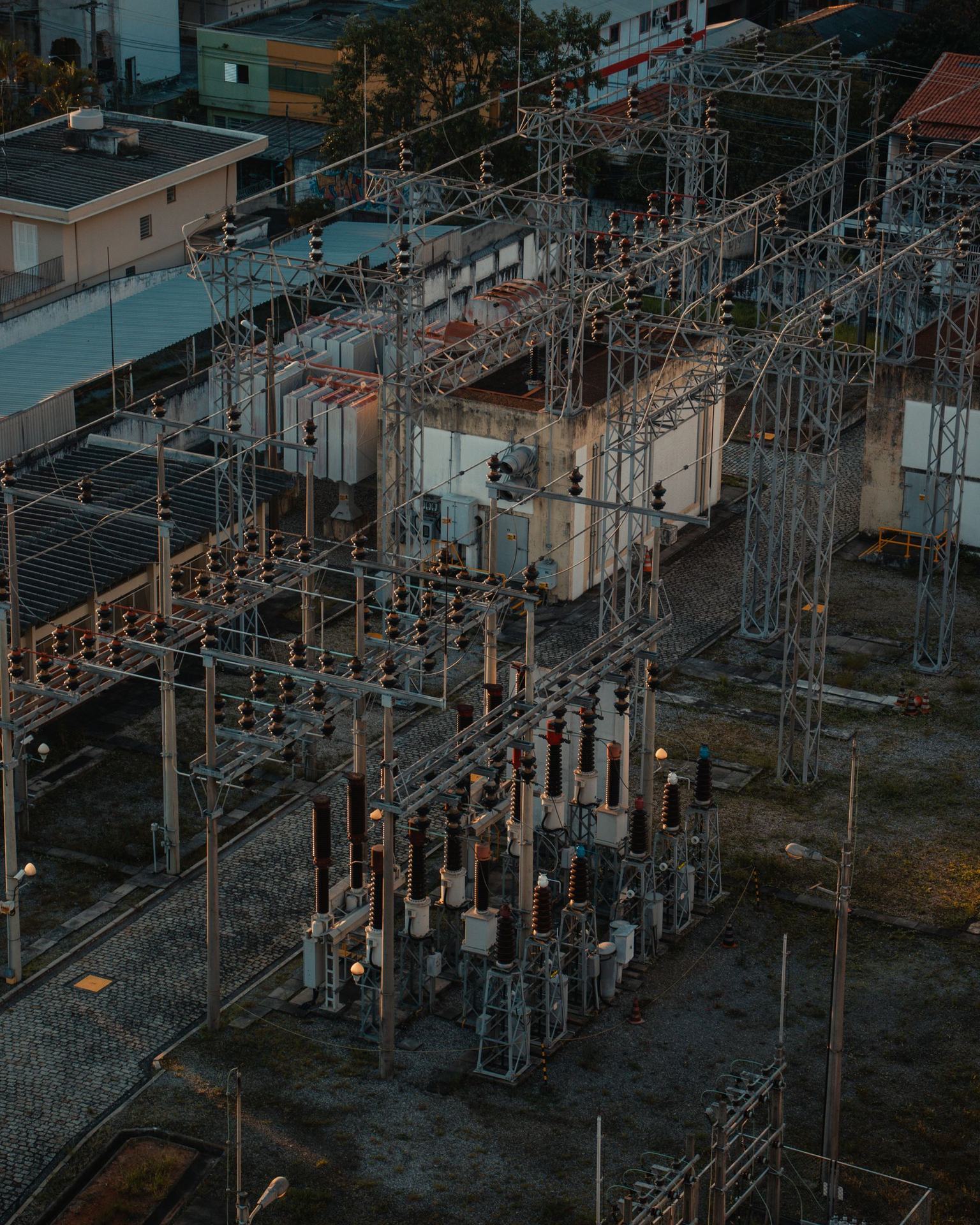 Aerial view of a substation yard at dusk, with switchgear, gantries and overhead lines